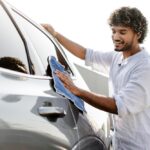 Car owner carefully cleaning a freshly repaired vehicle from an auto body shop in Brooklyn NY after collision repairs