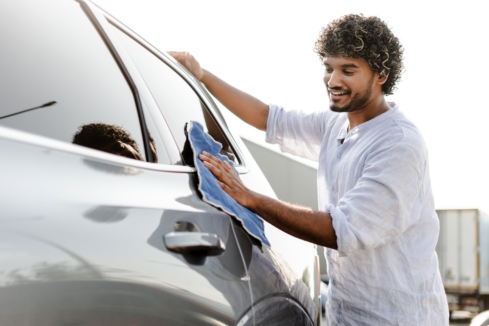 Car owner carefully cleaning a freshly repaired vehicle from an auto body shop in Brooklyn NY after collision repairs