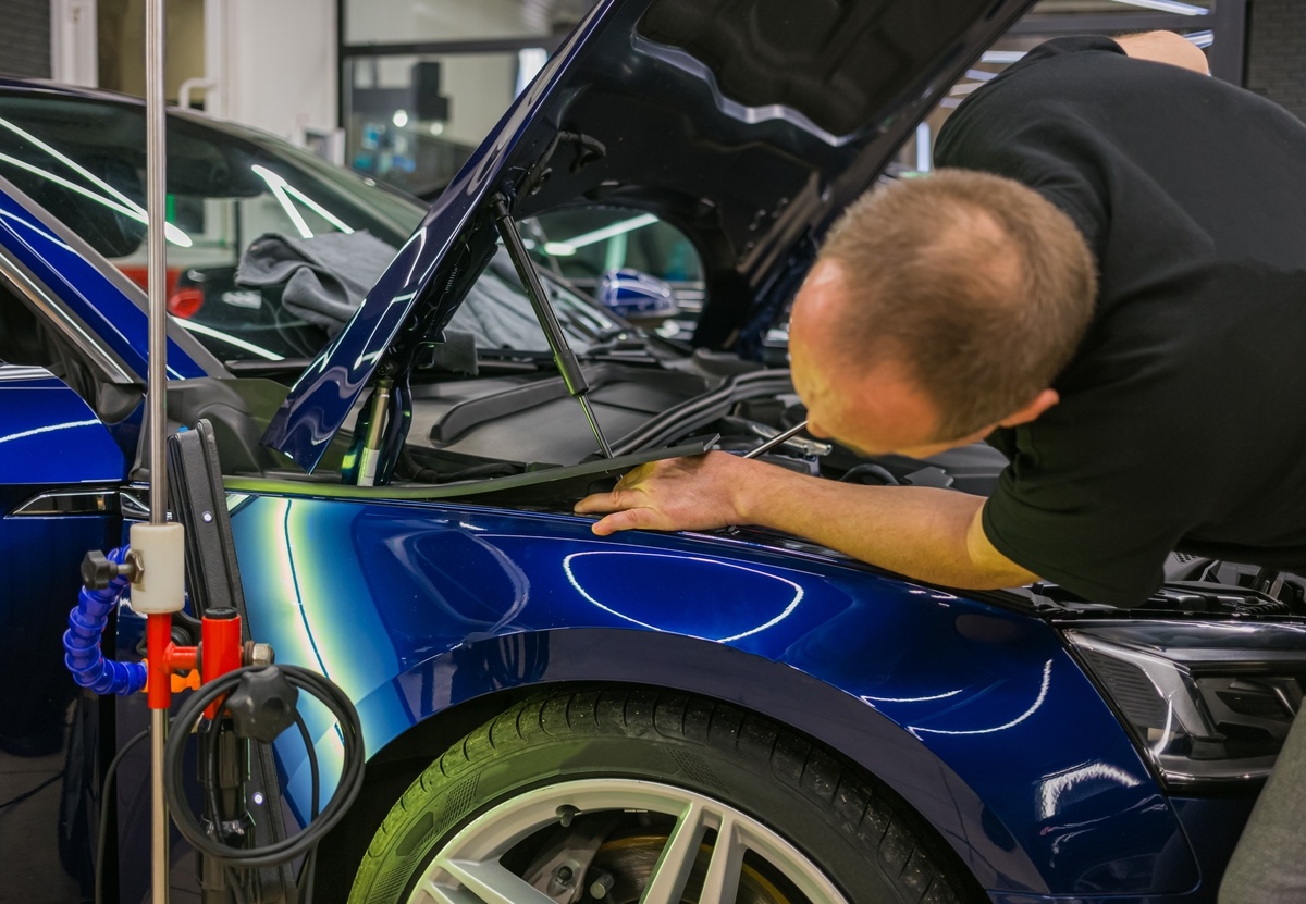 Auto body shop Brooklyn NY technician inspecting hood damage at Cyclone Collision Center