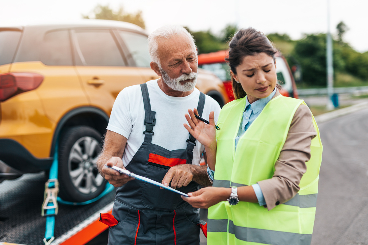What Happens if You Cannot Pay the Towing Bill in Brooklyn, New York? 14 Driver reviewing towing bill paperwork with a tow truck operator roadside — cannot pay the towing bill in Brooklyn