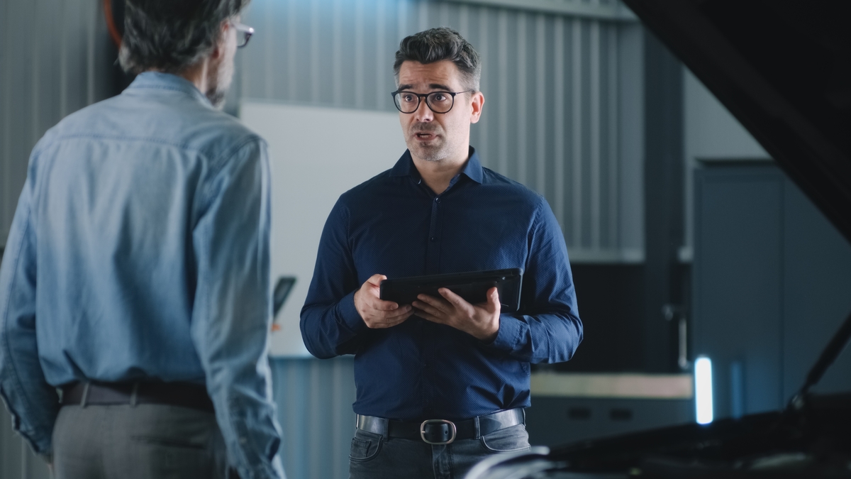 What Questions Should You Ask an Auto Body Shop Before Agreeing to Repairs? 15 Mechanic reviewing a written repair estimate with a customer at an auto body shop before agreeing to repairs — questions to ask auto body shop