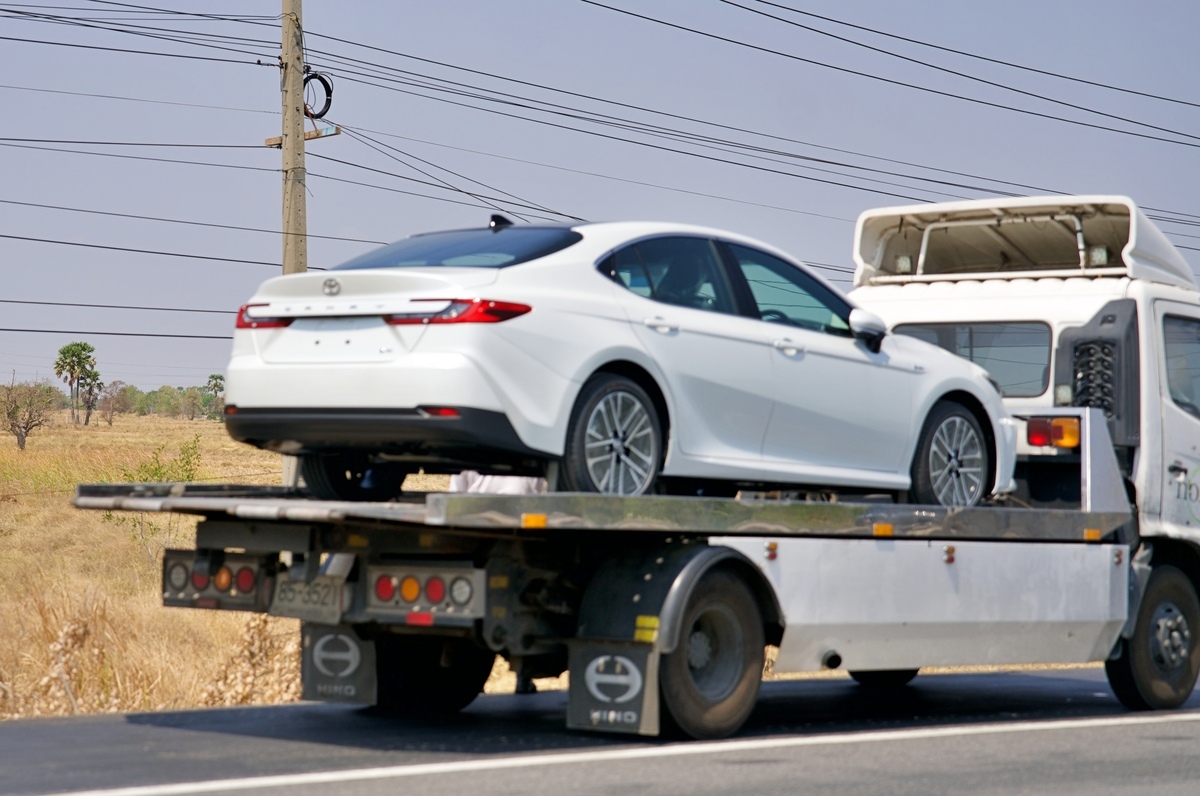White sedan loaded on a flatbed tow truck representing a car towed in Brooklyn NY