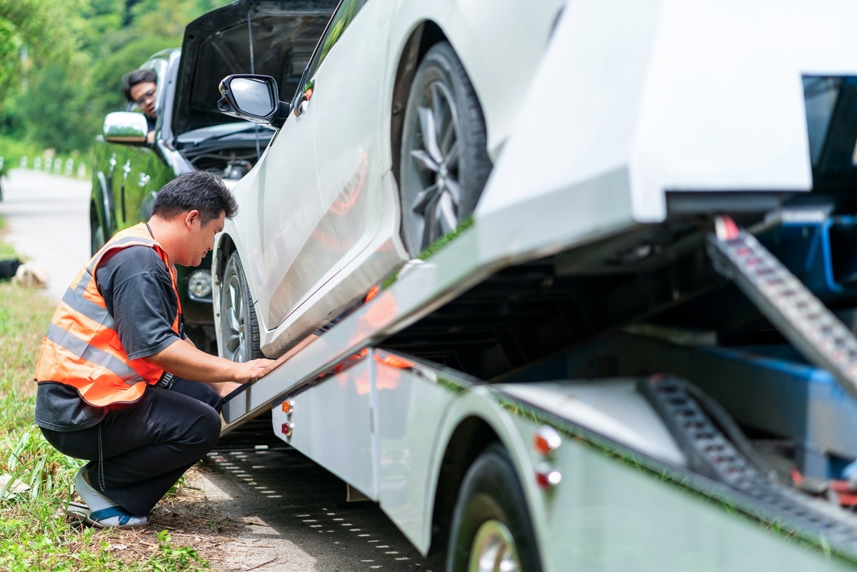 Tow truck operator loading a vehicle onto a flatbed during a non-consensual tow in New York roadside