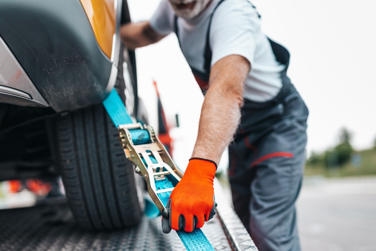 Tow truck operator securing a vehicle with straps, illustrating the towing bill in New York process