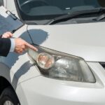 Professional appraiser with clipboard inspecting vehicle exterior panel for auto body repair resale value assessment