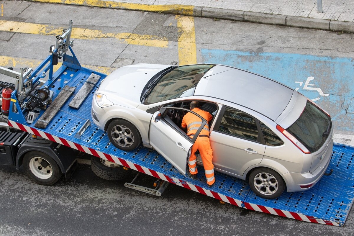 What Happens to Your Personal Belongings When Your Car Is Towed 11 Tow truck operator accessing interior of car on flatbed illustrating concerns about personal belongings when towed
