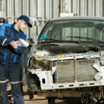 Auto body shop collision repair technician inspecting hidden radiator and structural damage