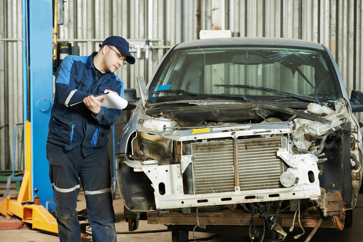 Auto body shop collision repair technician inspecting hidden radiator and structural damage