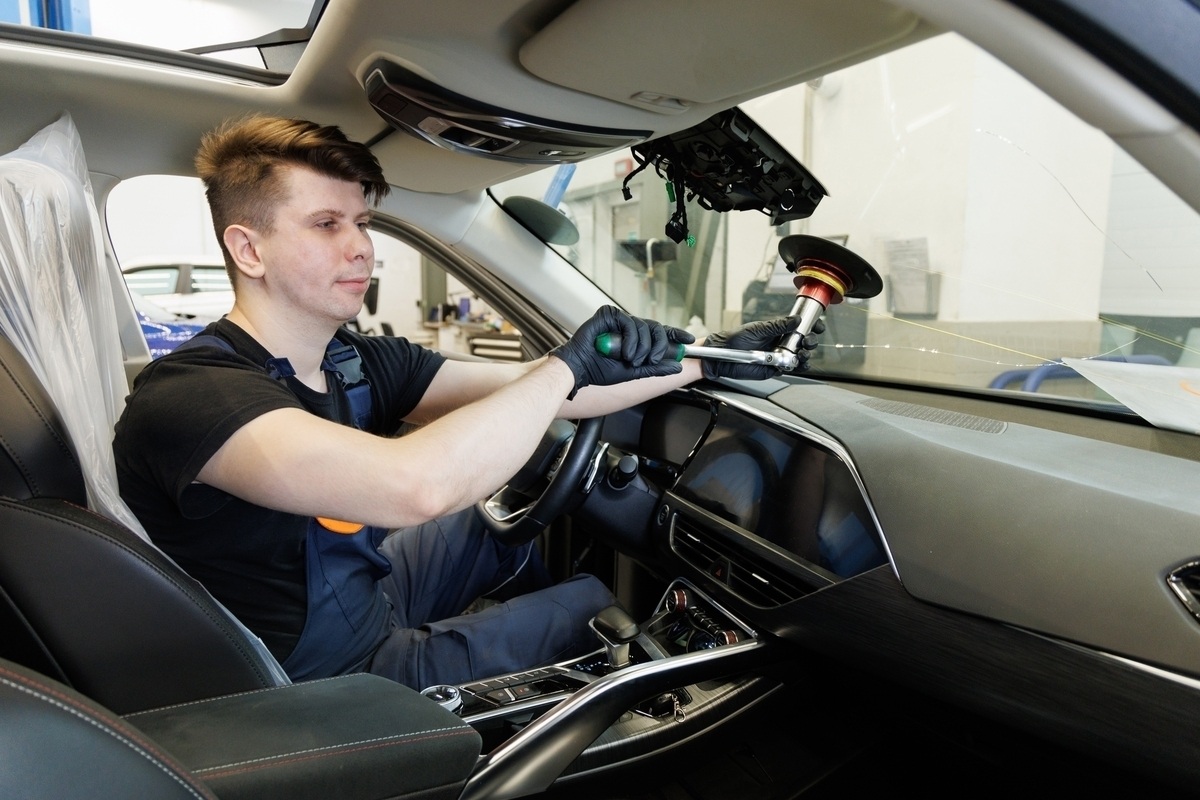 What an Auto Body Shop Does for Auto Glass Repair and Replacement 11 Technician working on windshield ADAS sensor during auto body shop glass replacement inside modern vehicle