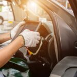 Technician using OBD diagnostic scanner inside vehicle for auto body shop electrical repair after a crash